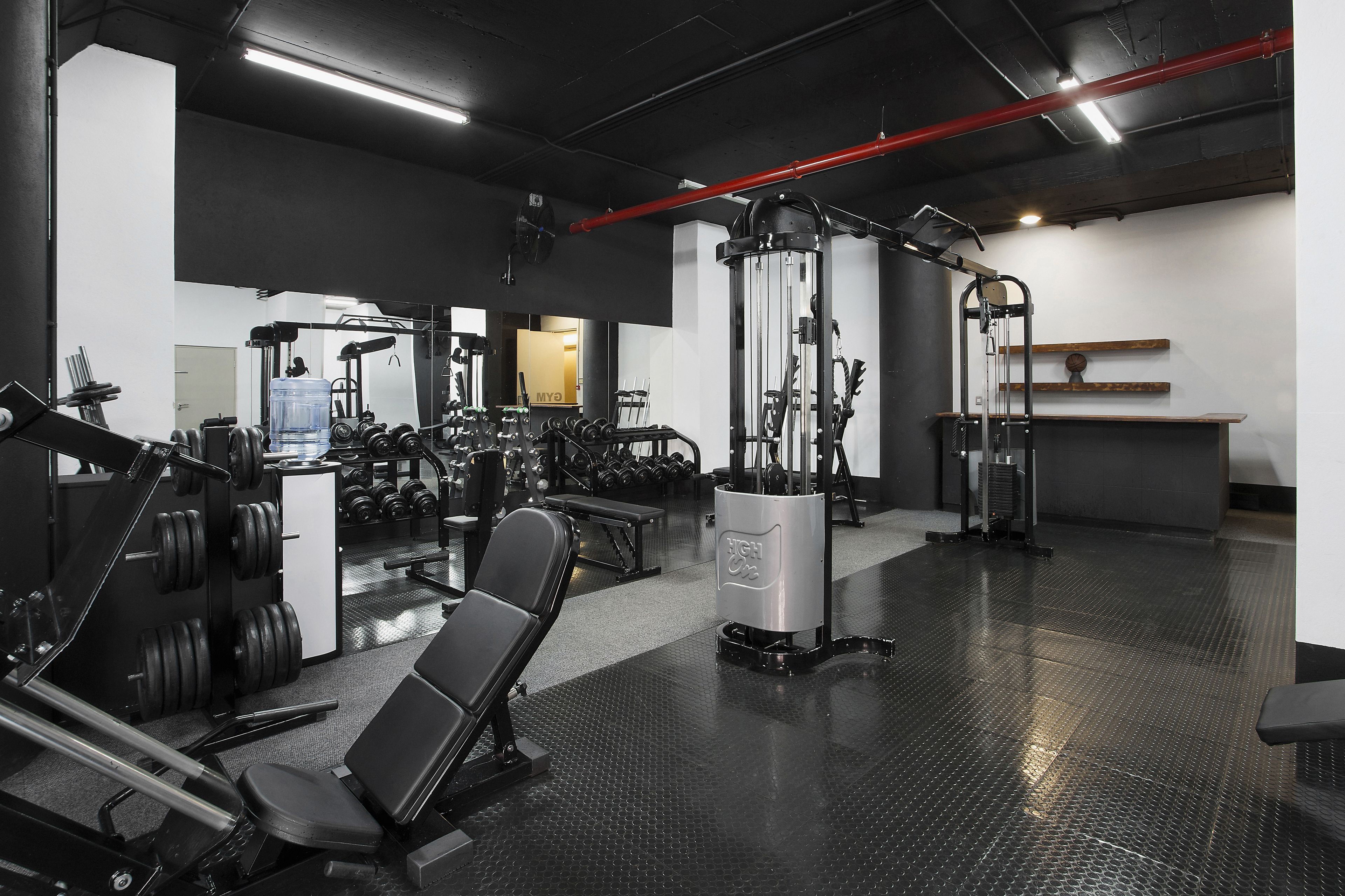 A gym with various exercise equipment, including weight machines, benches, and dumbbells.