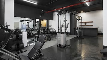 A gym with various exercise equipment, including weight machines, benches, and dumbbells.