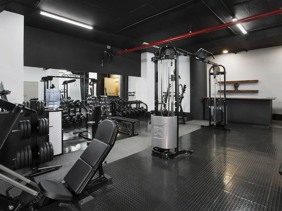 A gym with various exercise equipment, including weight machines, benches, and dumbbells.