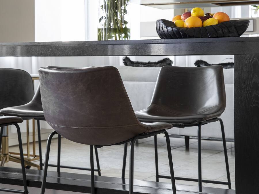 A modern kitchen with a black countertop, two bar stools, and a vase with flowers.