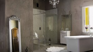 Une salle de bain moderne avec une baignoire sur pieds, un grand miroir et un lustre.