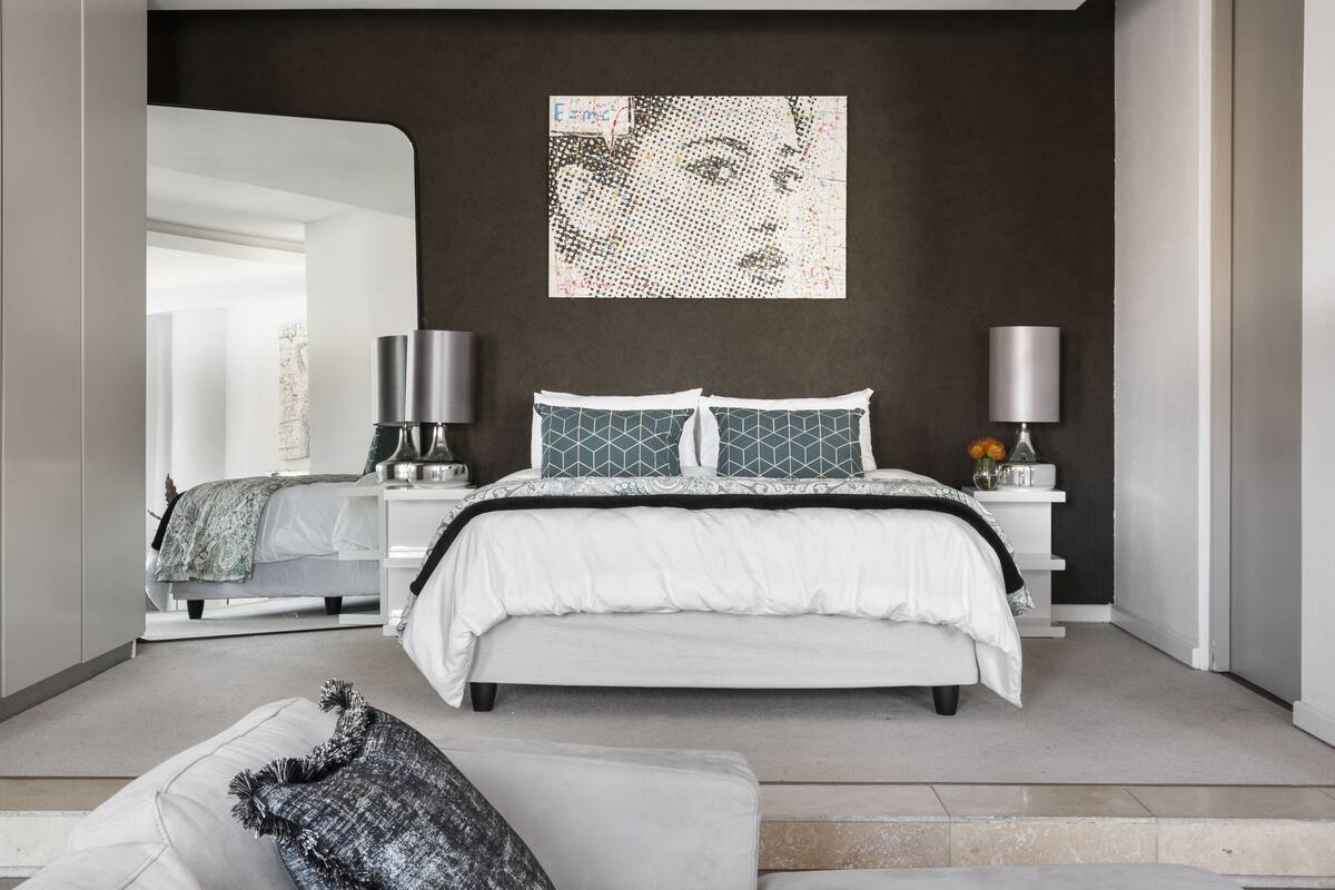 Een moderne slaapkamer met een groot bed, twee nachtkastjes en een kunstwerk aan de muur.