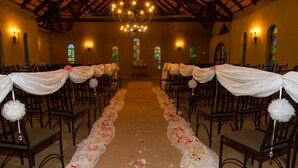 An aisle with chairs on both sides, a floral carpet, and a chandelier.