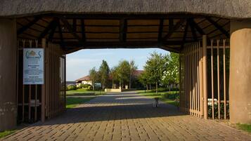 A covered entrance with a sign, a paved pathway, and a small dog in the distance.