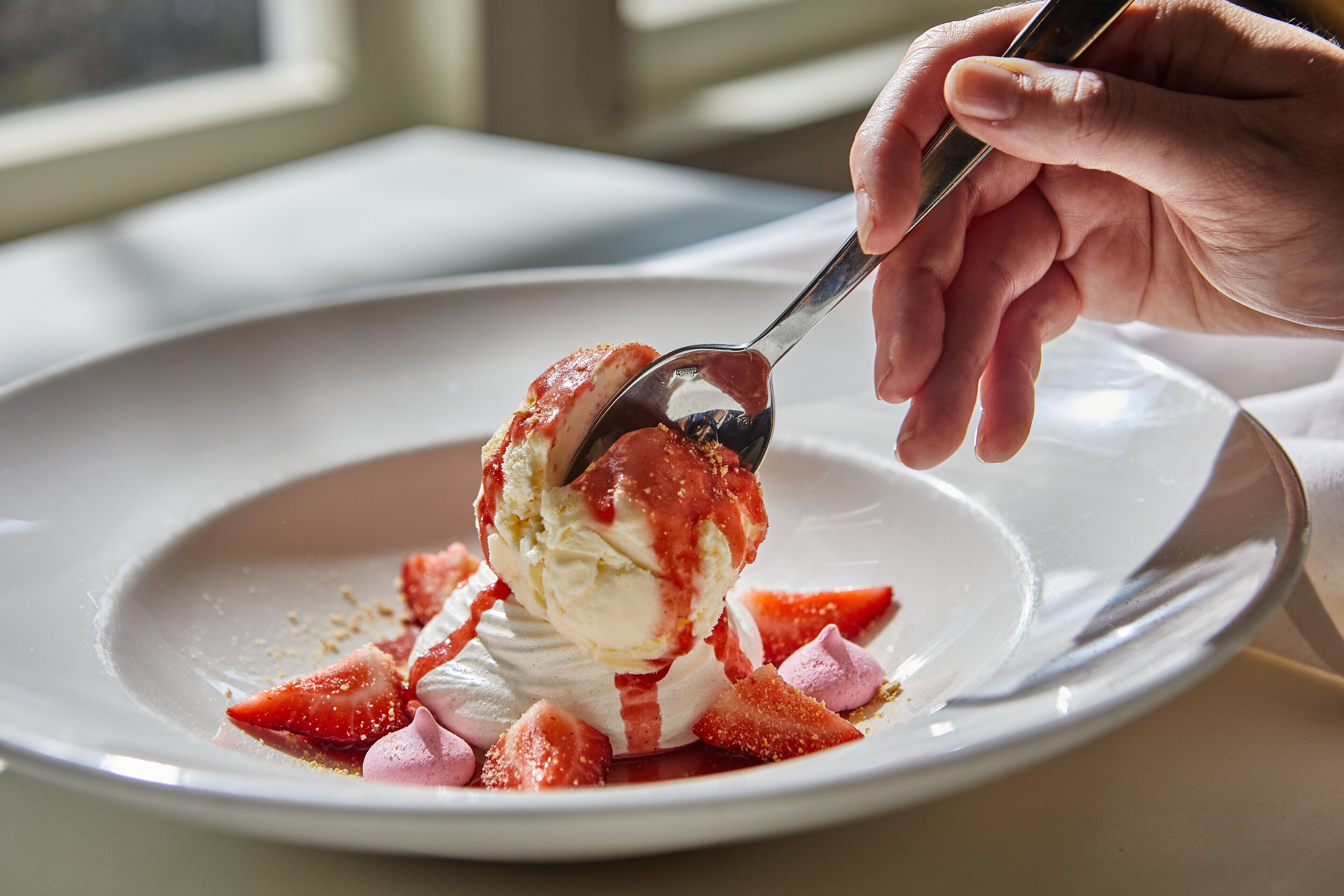 Un postre con helado y fresas en un plato.