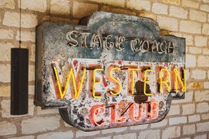 A weathered neon sign for the Stagecoach Western Club, mounted on a brick wall.