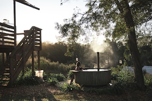 Een hottub in een tuin met een houten terras en een trap.