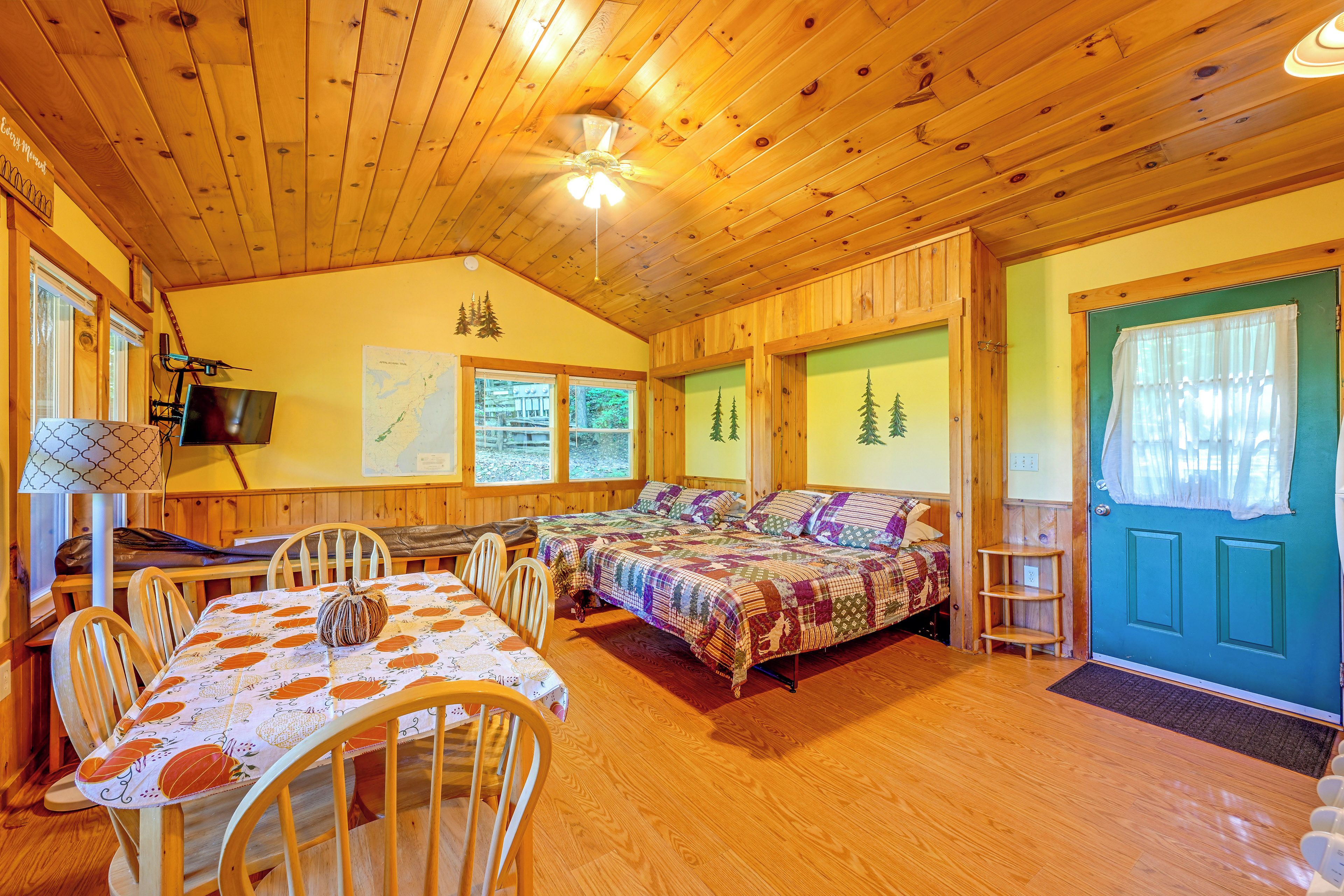 Ein gemütliches Blockhaus-Interieur mit Essbereich, einem Bett mit Patchwork-Quilt und einem Fernseher.