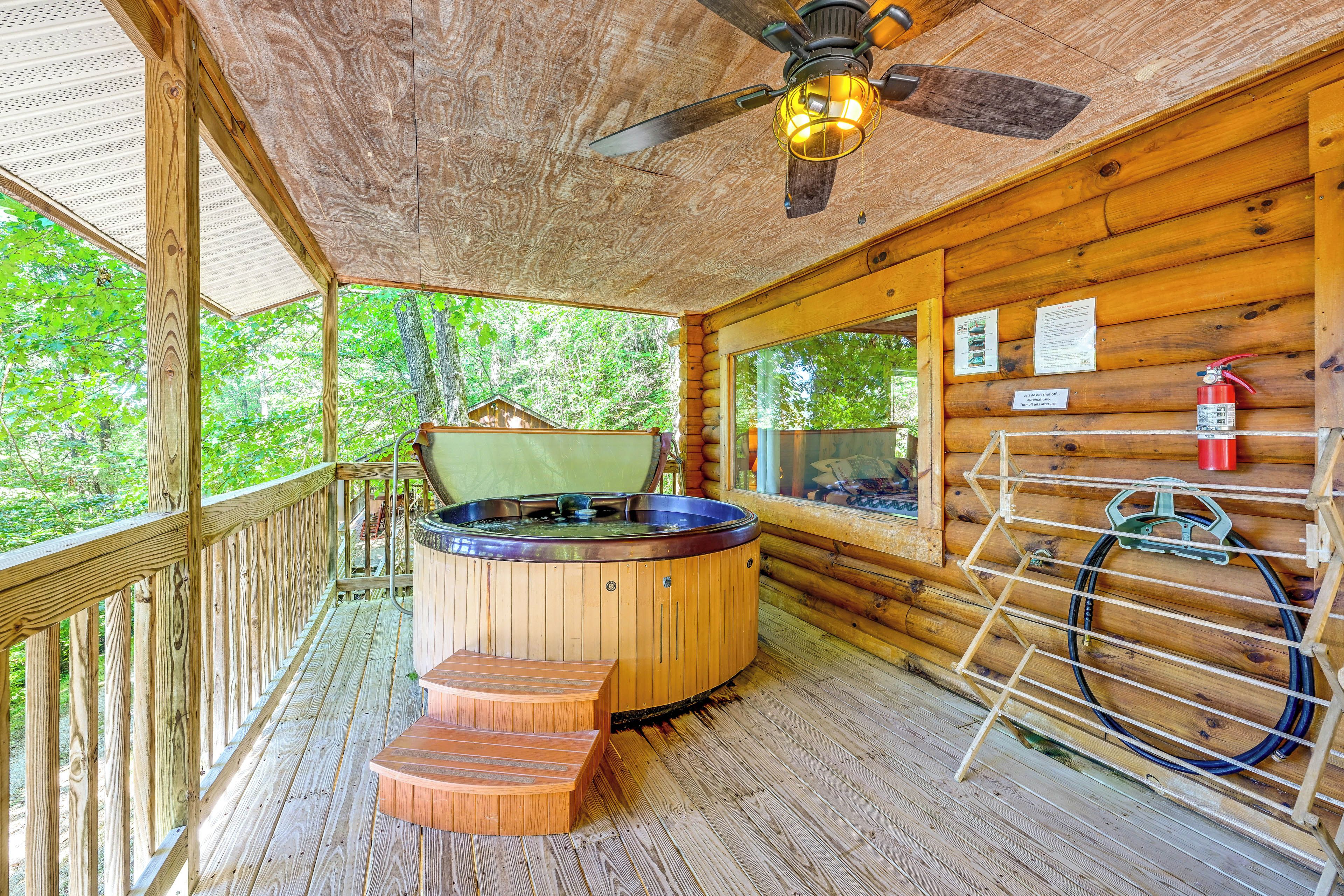 A wooden cabin with a hot tub, a ceiling fan, and a fire extinguisher.