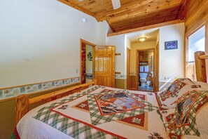 Ein Schlafzimmer mit einem großen Bett, Holzboden und Blick ins Badezimmer.
