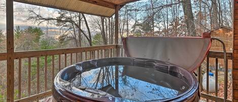 Un jacuzzi en una terraza de madera con vistas a árboles y colinas.