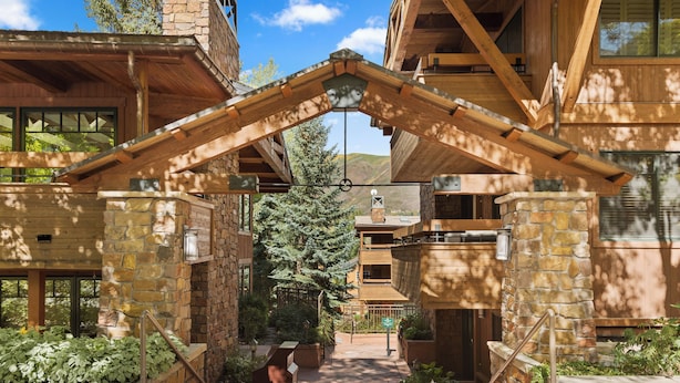 A wooden building with a stone facade, a central staircase, and a view of the surrounding landscape. - Modern Ski-in/Ski-out Condo with Pool and Hot Tub Access (Aspen)
