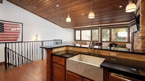 A kitchen with wooden ceiling, a large window, and a black countertop. - Modern Ski-in/Ski-out Condo with Pool and Hot Tub Access (Aspen)