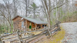 Un chalet rustique doté d’une véranda, entouré d’arbres.