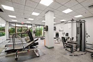 A gym with treadmills, weight machines, and exercise mats. - Beachfront 2BR/2BA condo with pool, WiFi, and heated pool (Marco Island)