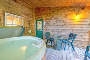 L’intérieur d’un chalet en bois, avec un bain à remous, deux chaises, une table et une porte.