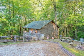 Eine rustikale Holzhütte mit Kiesweg, umgeben von dichtem Wald.