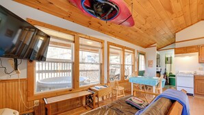 Interior acogedor de una cabaña con techo de madera, ventanas amplias, comedor y cocina.