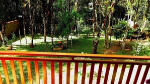 A fenced outdoor area with trees and a small garden. - Chalé Stillo (Gramado)