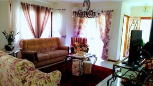 A living room with a sofa, armchair, coffee table, and a television. - Chalé Stillo (Gramado)