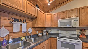 Una cocina con armarios de madera, un fregadero de acero inoxidable, un microondas y un horno.