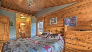 Un dormitorio de cabaña de madera con cama, paredes de madera y ventilador de techo.