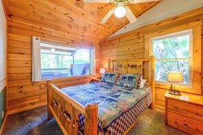A wooden cabin bedroom with a bed, a window, and a ceiling fan. - 'Bear Den' Cabin: Hot Tub, 4 Mi to Nantahala River (Bryson City)