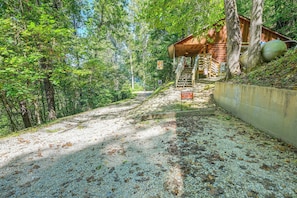 A gravel path leading to a cabin with a wooden exterior, surrounded by dense forest. - 'Bear Den' Cabin: Hot Tub, 4 Mi to Nantahala River (Bryson City)