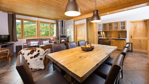 A spacious dining area with a wooden table and chairs, a fireplace, and a view of the outdoors. - Beautiful location with indoor swimming pool, wellness area & breathtaking view (Ventron)