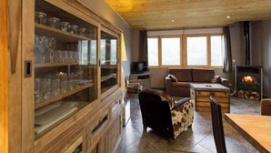 A cozy living room with a wooden cabinet, leather sofa, and a fireplace. - Beautiful location with indoor swimming pool, wellness area & breathtaking view (Ventron)