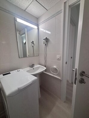 Ein Badezimmer mit zwei Waschbecken, einem Spiegel, einem Föhn und einem Handtuchhalter.