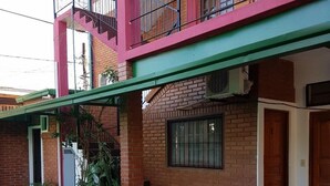 A two-story building with a brick facade, a green awning, and a tiled patio area. - Apart hotel Las Guayabas (Puerto Iguazú)