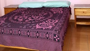 A bedroom with a bed, green curtains, a wooden nightstand, and a small wooden table. - Apart hotel Las Guayabas (Puerto Iguazú)