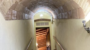 Un escalier surmonté d’une arche en briques, menant à une pièce dont le sol est recouvert de planches de bois.