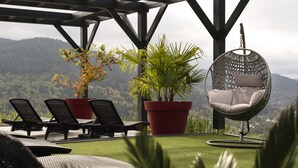 A patio with outdoor furniture, including lounge chairs and a hanging chair, surrounded by potted plants and a view of a mountainous landscape. - Vacation Rental for 10 People: 4 Bedrooms, Indoor Pool, Sauna, Fitness Center in Ventron, Vosges (Ventron)