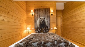 A wooden-paneled room with a large bear painting on the wall, two bedside lamps, and a fluffy brown blanket on the bed. - Vacation Rental for 10 People: 4 Bedrooms, Indoor Pool, Sauna, Fitness Center in Ventron, Vosges (Ventron)