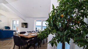 Un coin repas avec une table en bois dressée pour quatre personnes, entourée de chaises, et un citronnier en pot placé au premier plan.