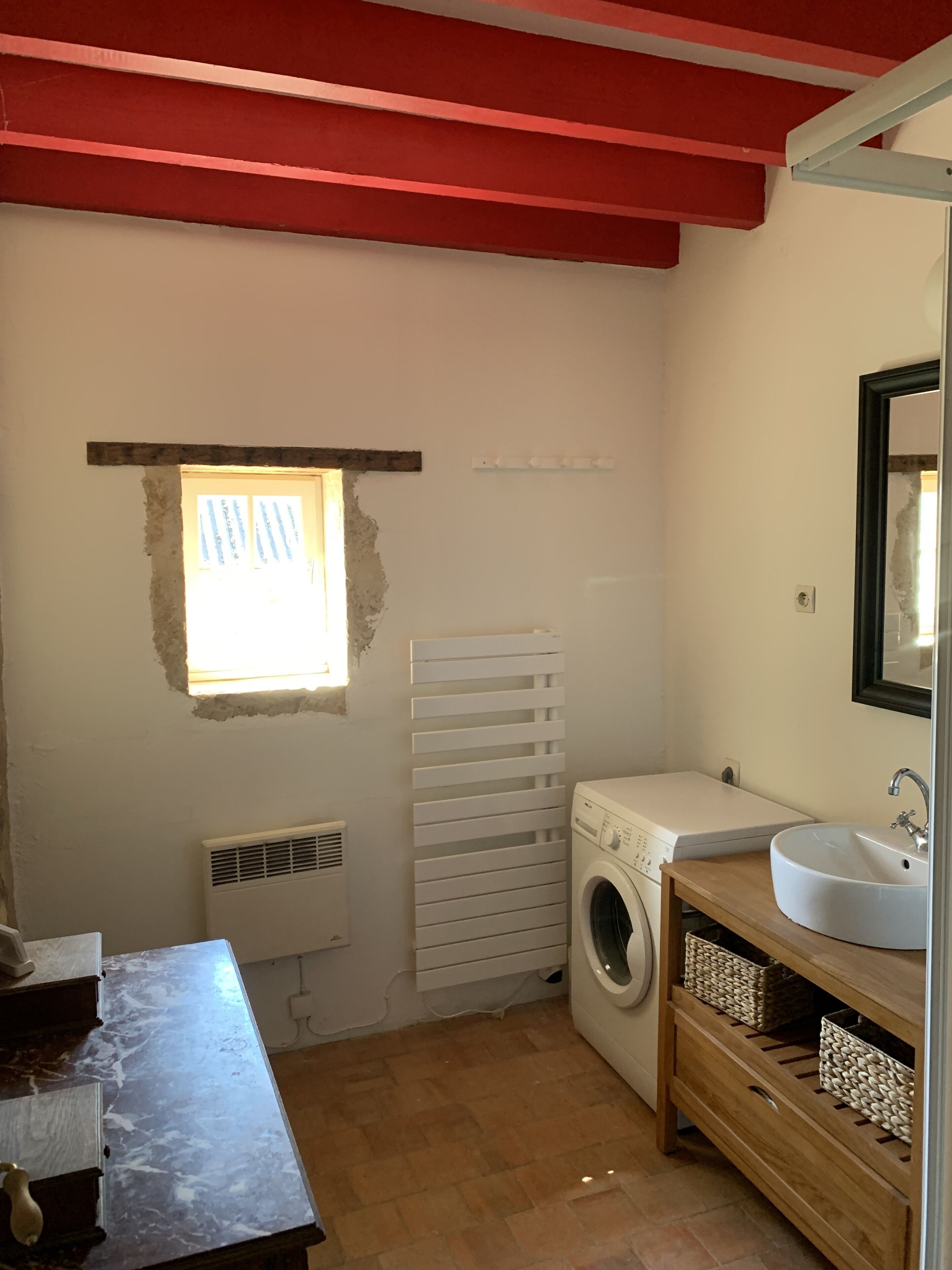 A small, compact bathroom with a washing machine, a sink, and a window.