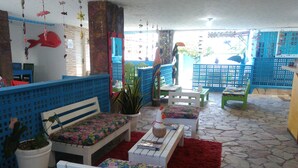 A room with a stone floor, white furniture, and blue and red decor. - Pousada Aquários do Porto (Ipojuca)