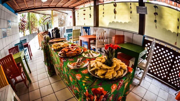 A buffet area with a variety of food items and a tropical-themed tablecloth. - Pousada Aquários do Porto (Ipojuca)