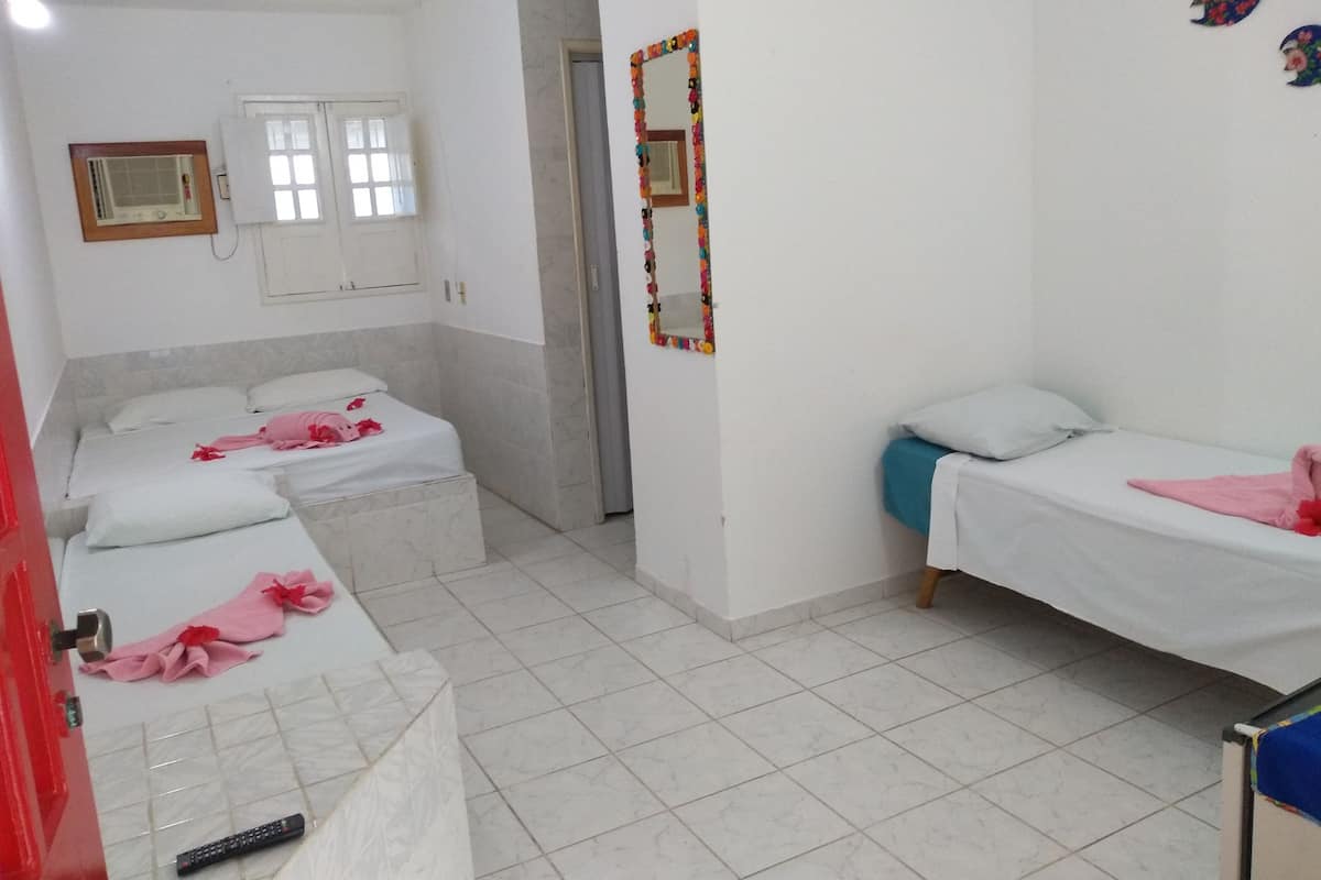 A room with two beds, a mirror, and a window.