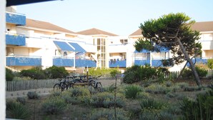 A residential building with multiple balconies, a central staircase, and a garden area with various plants and bicycles. - Apartment by the sea, Bleu Marine Lacanau Ocean residence France (Lacanau Océan)
