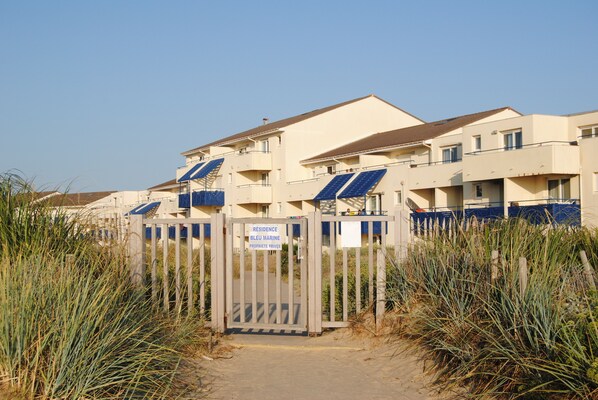 A residential building with a gated entrance, solar panels on the roof, and a sign indicating private property.
