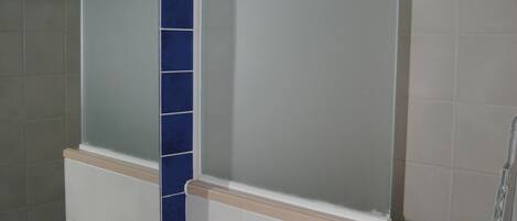 A bathroom with a beige sink, a mirror, and blue-tiled walls.