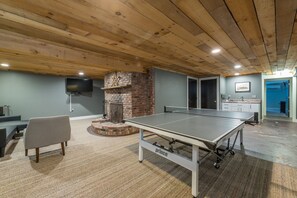 Relax in a cozy space with a ping pong table, comfortable seating, and a brick fireplace.