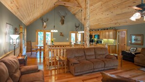 Un intérieur rustique avec un plafond en bois, un canapé en cuir marron et des bois de cerf accrochés au mur.