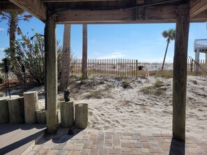 A wooden deck with a view of the beach and a fence.