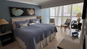A bedroom with a bed, nightstands, a ceiling fan, and a view through large windows. - Paradise Found, Unique Location (Key Biscayne)