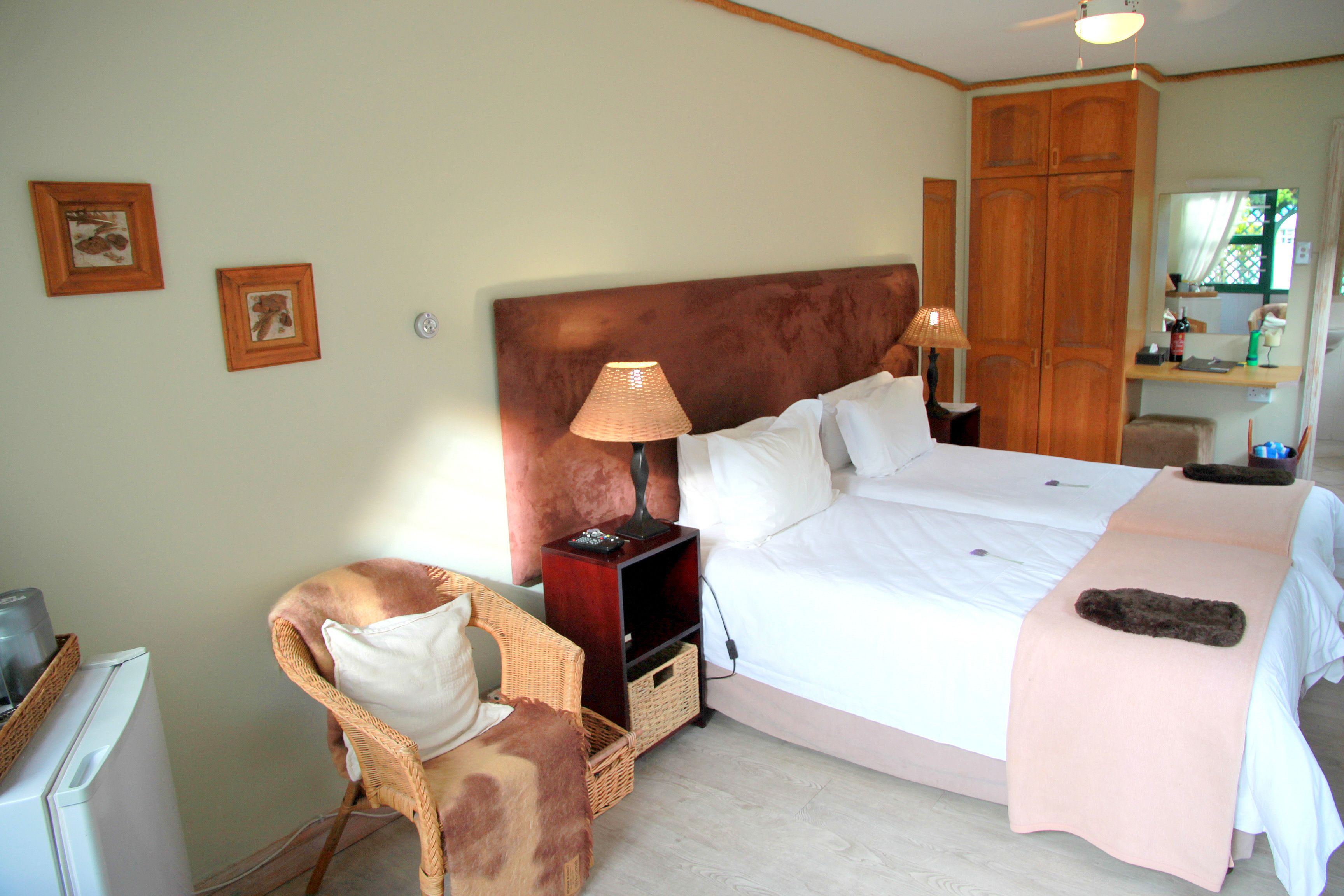 Une chambre à coucher avec un grand lit, deux tables de chevet, une chaise, une armoire et une petite table avec une lampe.