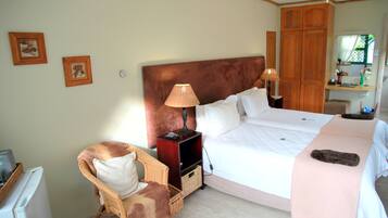 Une chambre à coucher avec un grand lit, deux tables de chevet, une chaise, une armoire et une petite table avec une lampe.